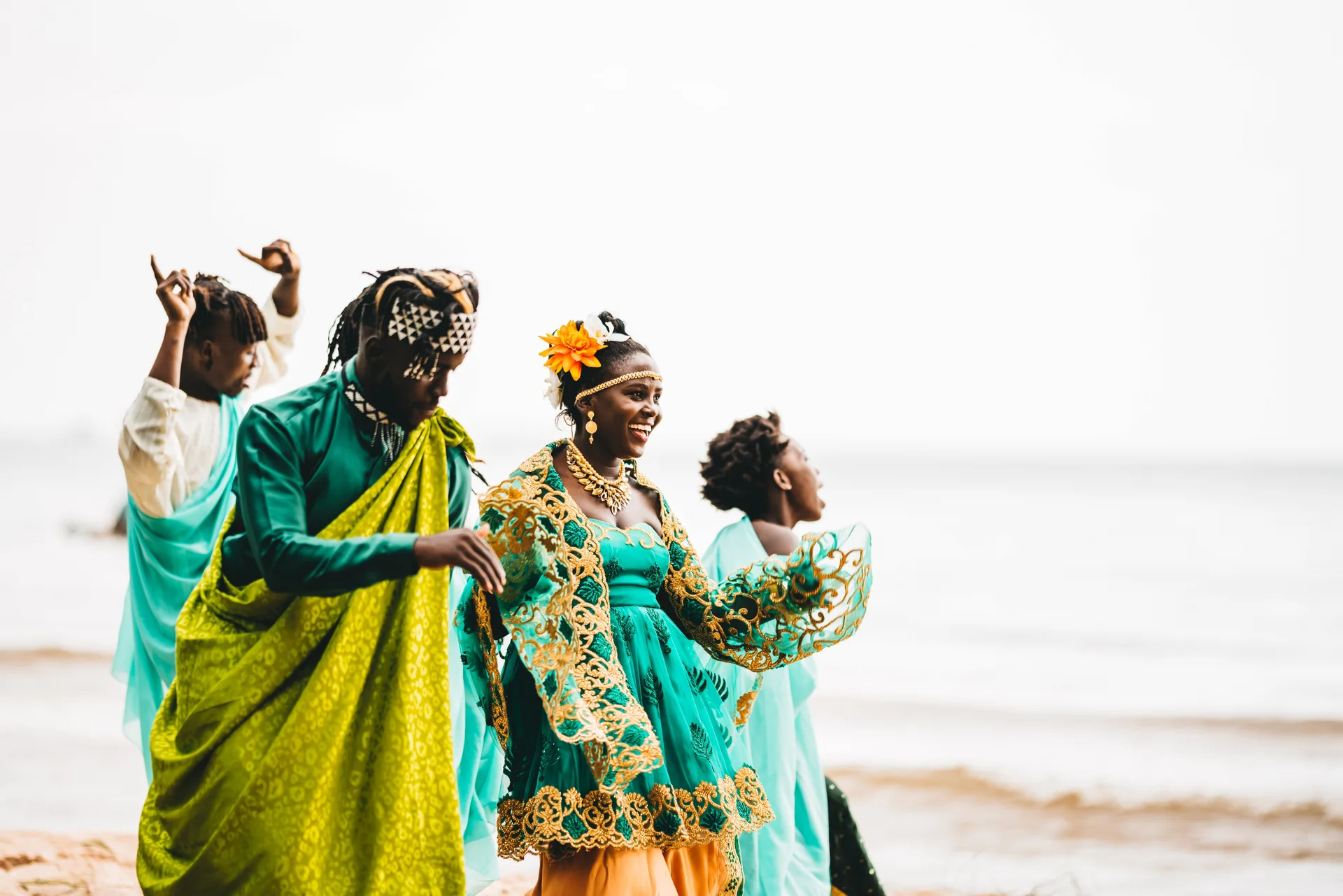People dancing outdoors in turquoise, green and gold attire